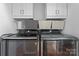 Modern laundry area with gray front-loading machines, white cabinets, and stylish storage baskets at 307 Tara Elizabeth Pl # 22, Kannapolis, NC 28083