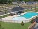 Aerial view of the community pool with a splash pad, lounge chairs, fenced perimeter, and nearby houses at 111 Sentinel Ct, Mooresville, NC 28115