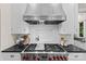 Close up of stainless steel range with hood, subway tile, and dark countertops in this modern kitchen at 1579 Queens W Rd, Charlotte, NC 28207
