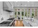 Modern kitchen features an island, farmhouse sink, stainless steel range, and large windows with backyard views at 1579 Queens W Rd, Charlotte, NC 28207