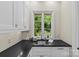 Charming laundry room with black countertops, white cabinetry, and a bright window overlooking the garden at 1579 Queens W Rd, Charlotte, NC 28207