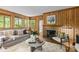 Cozy living room featuring wood paneling, a fireplace, and an abundance of natural light from the surrounding windows at 1579 Queens W Rd, Charlotte, NC 28207