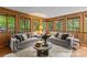 Bright living room with wood paneled walls and multiple windows providing natural light and views of the surrounding greenery at 1579 Queens W Rd, Charlotte, NC 28207