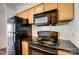 Kitchen features wooden cabinets, black appliances, and black countertops at 2514 Cranbrook Ln # 9, Charlotte, NC 28207