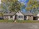 Charming single-story home with a stone and stucco facade, surrounded by mature trees and a well-manicured lawn at 406 Harris Ln, Monroe, NC 28112