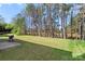 Scenic backyard featuring well-maintained lawn and mature trees, with grill on patio at 3015 Hendricks Chapel Ln, Charlotte, NC 28216