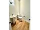 Compact powder room featuring a pedestal sink, a standard toilet, and modern fixtures, all on hardwood floors at 3850 Willow Grove Ln # 24, Concord, NC 28025
