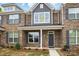 Charming brick townhome featuring gray shutters, craftsman columns, and professionally landscaped yard at 5527 Stafford Rd # 34, Charlotte, NC 28215