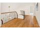 Second floor hallway with hardwood floors, wrought iron railing, and a decorative chandelier hanging from the ceiling at 1716 Funny Cide Dr, Waxhaw, NC 28173