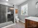 Bathroom features a tiled glass shower, wood vanity and cabinet, toilet, and a window for natural light at 204 Jonas Dr, Lincolnton, NC 28092