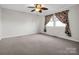 Carpeted bedroom featuring a ceiling fan, window with decorative curtains, and plenty of natural light at 204 Jonas Dr, Lincolnton, NC 28092