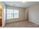 Bright bedroom with neutral walls and carpet features a sun-filled window, and access to the bathroom at 7108 Kinley Commons Ln, Charlotte, NC 28278