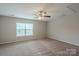 Bright bonus room with neutral walls and carpet features a ceiling fan and a sun-filled window at 7108 Kinley Commons Ln, Charlotte, NC 28278