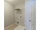 Bright laundry room with tile flooring, white shelving, and washer/dryer hookups ready for customization at 7108 Kinley Commons Ln, Charlotte, NC 28278