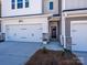 View of the townhome entrance featuring stone accents, a two-car garage, and a welcoming front door at 153 Halite Ln, Waxhaw, NC 28173