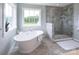Bright bathroom featuring a standalone tub, tiled floor and walls, and a walk-in shower at Lot 51 Watercourse Way # Covington, Belmont, NC 28012