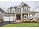 Charming two-story residence showcasing stone accents, a covered porch, a turret, and an attached three-car garage at Lot 51 Watercourse Way # Covington, Belmont, NC 28012