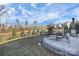 Spacious backyard featuring a stone patio with a fire pit, lounge chairs, and dining set surrounded by trees at 913 Deep River Way, Waxhaw, NC 28173