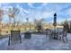 View of a patio with a stone fire pit, seating area and dining table with a partly cloudy sky above at 913 Deep River Way, Waxhaw, NC 28173