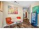 Bright dining area with an artistic painting and two orange chairs. Hallway and beverage cooler also visible at 210 N Church St # 2702, Charlotte, NC 28202