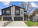 Contemporary house with a sleek design, featuring a stone base, dark garage doors and lush green lawn at 2205 Catalina Ave, Charlotte, NC 28206