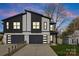 Modern home with a two-car garage, stone accents, and gray siding against a colorful evening sky at 2205 Catalina Ave, Charlotte, NC 28206