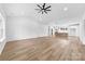Open-concept living space featuring wood floors, fan, and white walls; kitchen in the background at 1300 Eddie St, Gastonia, NC 28054