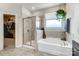 Bathroom featuring a walk-in shower, soaking tub, window and hanging pothos plant at 6012 Drave Ln, Fort Mill, SC 29715