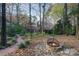 Backyard scene featuring a fire pit with a stone surround and a red wood chip path leading towards the house at 21315 Blakely Shores Dr, Cornelius, NC 28031