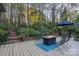 Backyard deck with a fire table and seating nestled amongst trees and lush greenery with wooden stairs leading up the hill at 21315 Blakely Shores Dr, Cornelius, NC 28031