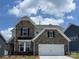 Two-story home showcasing a stone facade, a two-car garage, and manicured landscaping at 1476 Hubert Graham Way, Tega Cay, SC 29708