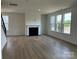 Open living room featuring a fireplace, large windows, and hardwood floors at 1476 Hubert Graham Way, Tega Cay, SC 29708