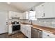 Modern kitchen with stainless steel appliances, white cabinets, butcher block countertops, and a farmhouse sink at 161 Westscott Dr, Statesville, NC 28625