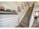 Carpeted staircase with wood railing, black iron spindles, and decorative wainscoting leads to the upper level at 3877 Lake Breeze Dr, Sherrills Ford, NC 28673