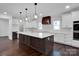 Modern kitchen featuring white cabinets, quartz countertops, and a statement hood at 3907 E Lawyers Rd, Monroe, NC 28110