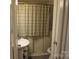 Compact bathroom featuring a pedestal sink, neutral walls, and a shower with a plaid curtain at 155 6Th Sw St, Taylorsville, NC 28681