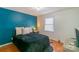 Cozy bedroom with a teal accent wall, comfortable bed, and natural light from the window at 405 Wakefield Dr # B, Charlotte, NC 28209