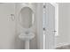 A simple, modern powder bathroom featuring a pedestal sink, oval mirror, and white door at 5019 Layman Dr # 26, Charlotte, NC 28226