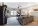 Comfortable living room with a ceiling fan, a couch, windows, and decorative items on shelves at 16515 Governors Club Ct, Charlotte, NC 28278