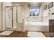 This bathroom features tile floors, a large soaking tub, a glass door shower, and a privacy window at 16515 Governors Club Ct, Charlotte, NC 28278