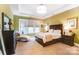 This main bedroom boasts neutral walls, carpet, a tray ceiling and a chaise lounge by the window at 16515 Governors Club Ct, Charlotte, NC 28278