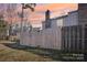 Backyard with wooden fence, green grass, and mature trees during sunset at 5300 Fair Wind Ln, Charlotte, NC 28212