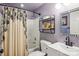 Cozy bathroom featuring purple walls, shower-tub combo with neutral colored shower curtain, and floating shelves at 5300 Fair Wind Ln, Charlotte, NC 28212