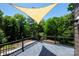 A spacious deck with gray tiles and a tan sunshade offers a serene outdoor living area surrounded by lush greenery at 6534 Providence Rd, Charlotte, NC 28226