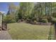 Manicured backyard featuring a stone retaining wall, mature trees, and lush lawn at 10029 Daufuskie Dr, Charlotte, NC 28278