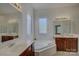 Elegant bathroom featuring double vanities, a soaking tub, and ample natural light at 10029 Daufuskie Dr, Charlotte, NC 28278