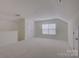 Upstairs bonus room with carpet, natural light, and attic storage access at 10029 Daufuskie Dr, Charlotte, NC 28278
