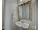 Charming half bathroom with a pedestal sink, decorative mirror, and clean white fixtures at 10029 Daufuskie Dr, Charlotte, NC 28278