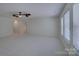 Spacious living room with large windows, ceiling fan, and neutral carpet at 10029 Daufuskie Dr, Charlotte, NC 28278
