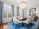 Elegant dining room with chandelier, hardwood floors, neutral walls, and blue rug and window dressings at 1655 Scotland Ave, Charlotte, NC 28207